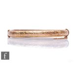 A 9ct hallmarked rose gold hinged bangle with foliate engraved decoration to front, weight 8.5g,