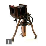 An early 20th Century 1/4 plate camera on wooden studio stand with crank handle.