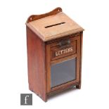 A late Victorian oak wall mounted letter box, the bevelled glass front mounted with the incised