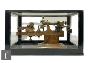 A 20th Century brass Lorch type watch makers lathe, with later wooden base and glazed case, unnamed,