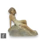 A 1930s Italian Art Deco figure of a reclining bathing belle in costume with wide brimmed hat