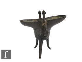 A Chinese Archaic style ritual wine vessel, Jue, of tripod form, rising to a scooped upper spout and