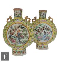 A pair of late 19th Century Chinese famille rose moonflasks, each raised from a high foot flanked by