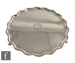 A hallmarked silver circular salver with central engraved crest and beaded decorated borders, weight