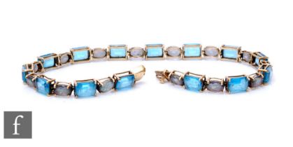 A 9ct hallmarked blue topaz and faux alexandrite flexible bracelet comprising twenty eight