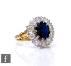An 18ct hallmarked sapphire and diamond cluster ring, central oval sapphire, length 9mm, within a