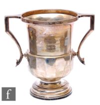 A hallmarked silver twin handled pedestal trophy cup with part panelled decoration below