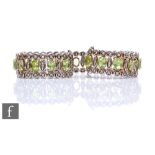 A silver peridot and white sapphire flexible bracelet, twenty one marquise cut peridot spaced and