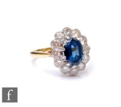 An 18ct sapphire and diamond cluster ring, central oval sapphire, length 8.5mm, within a border of