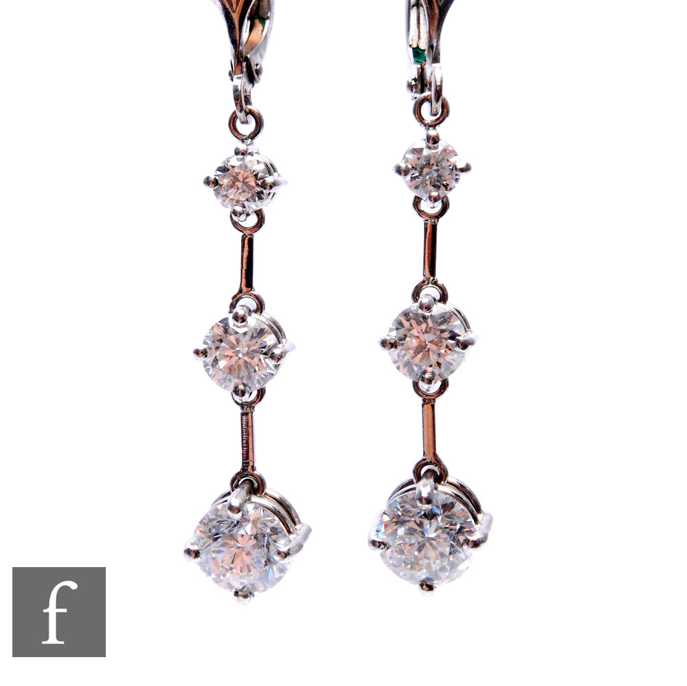 A pair of 18ct hallmarked white gold diamond drop earrings comprised of three graduated, brilliant
