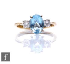 An 18ct hallmarked aquamarine and diamond three stone ring, central oval aquamarine flanked by a