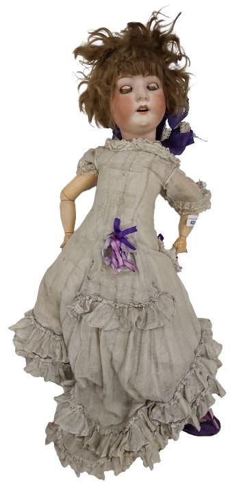 A late 19th Century porcelain Child's German Doll, marked, wearing linen dress and purple shoes,