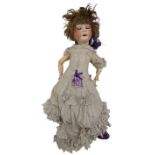A late 19th Century porcelain Child's German Doll, marked, wearing linen dress and purple shoes,