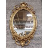 A 19th Century oval gilt Girandole Mirror, with shell crest issuing scrolling leaves on a bead