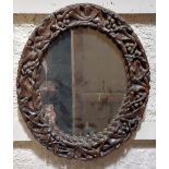 An oval rustic carved wooden Wall Mirror, with scrolling leaves and berries, 23'' x 19'' (59cms x