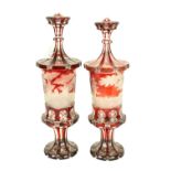 An extremely fine pair of Bohemian ruby Urns and Covers, c. 1870, each etched with a woodland scene,