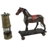 A composition Toy Horse, on rectangular wooden base with four cast iron wheels, 30cms (12");