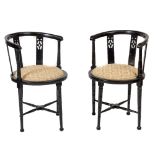 A pair of ebonised Aesthetic style Armchairs, each with a circular padded seat and pierced splats to