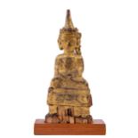 An early Burmese carved wooden and parcel gilt seated Buddha, 23cms (9") on later mahogany stand. (