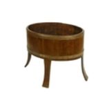 An oval brass bound Ash Planter, of coopered construction, on four bentwood splayed legs, 61cms x