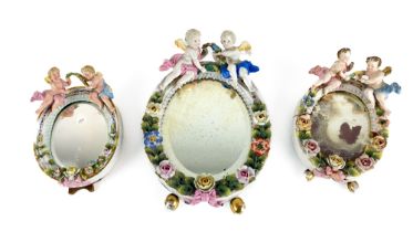An oval flower encrusted Sitzendorf porcelain Table Mirror, crested with two cherubs on gilt egg