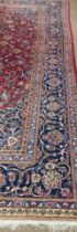 A large Middle Eastern burgundy ground woollen Carpet, the central panel with floral medallion