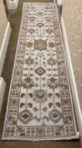 A cream ground woollen Runner, with floral decorated centre inside narrow conforming border, approx.