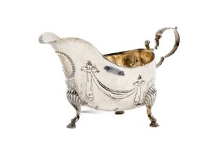 An Irish silver Sauceboat, embossed with hanging drapes and hammered bead work on S shell legs and
