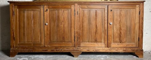 A large late 19th Century four door pitch pine Cupboard, with oblong moulded top raised on bracket