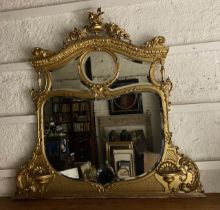 A late 19th Century ornate gilt Overmantel Mirror, crested with an urn issuing floral swags on an