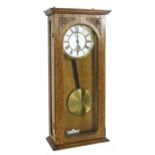Oak cased Vienna style electro-mechanical wall clock, fitted with a rectangular brass plaque to