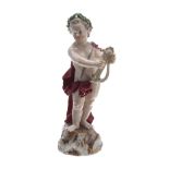 Meissen porcelain figure of a Putto, modelled standing playing a lyre, wearing a red cape and laurel