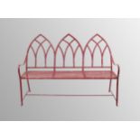 Gothic revival red painted wrought iron garden bench, with a triple lancet back over strapwork seat,