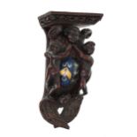 Antique carved corbel bracket, with scrolling foliate border over a support of three winged putti