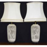 Pair of ornate reticulated porcelain table lamps with shades, decorated with prunus trees, the bases