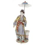 Berlin porcelain figure of a Japanese lady standing holding a parasol, with a pottery vase by her