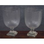Pair of cut glass urns, possibly Waterford, raised on faceted stems over stepped square bases, 8.