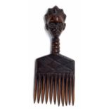 African tribal hardwood comb, with a carved mask handle and geometric decoration, 8" long