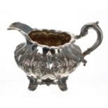 William IV silver cream jug, with a scrolling handle and flared rim, over a lobed melon shape body