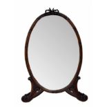 Mahogany oval strut dressing mirror, the plain glass within a reeded frame surmounted by a carved