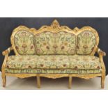Decorative large gilt settee, the scrolling shaped back over a triple panel upholstered back over