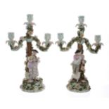 Pair of late 19th century German porcelain three-branch candelabra, the candle arms encrusted with