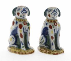 Pair of 18th century Dutch Delft pottery dog figures, freely painted with polychrome decoration,