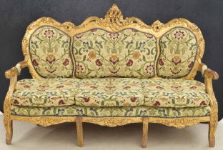 Decorative large gilt settee, the scrolling shaped back over a triple panel upholstered back over