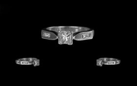 A Platinum Diamond Engagement Ring, set with a central princess cut diamond,