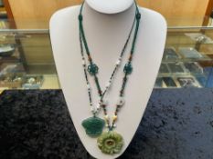 Two Green Jade Pendant Necklaces, one having a large, carved, floral pendant,