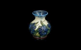 W. Moorcroft Small Vase. Blue & White Background with Blue Flowers and Green Stems.