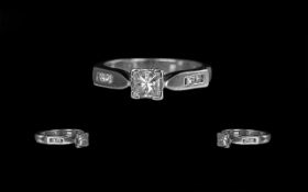 A Platinum Diamond Engagement Ring, set with a central princess cut diamond, four round cut