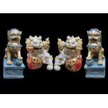 A Collection of Four Oriental Foo Dogs, two in resin on rectangular plinths, and two porcelain.