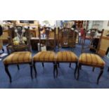 Four Early 20th Century Dining Chairs, with carved backrests depicting torches, stuffed seats,